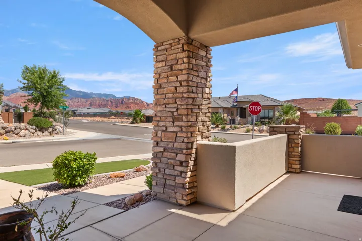 Front patio featuring a stone-clad pillar, stucco half-wall, and concrete flooring