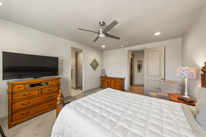 Spacious bedroom featuring light neutral wall tones, recessed lighting, and a ceiling fan