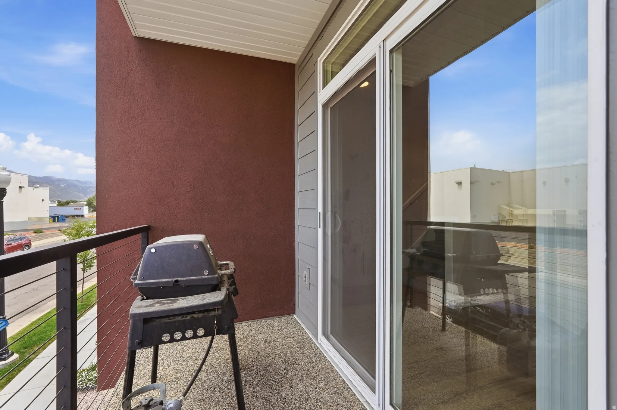 Private outdoor balcony featuring a textured concrete surface, metal railing, and a sliding glass door