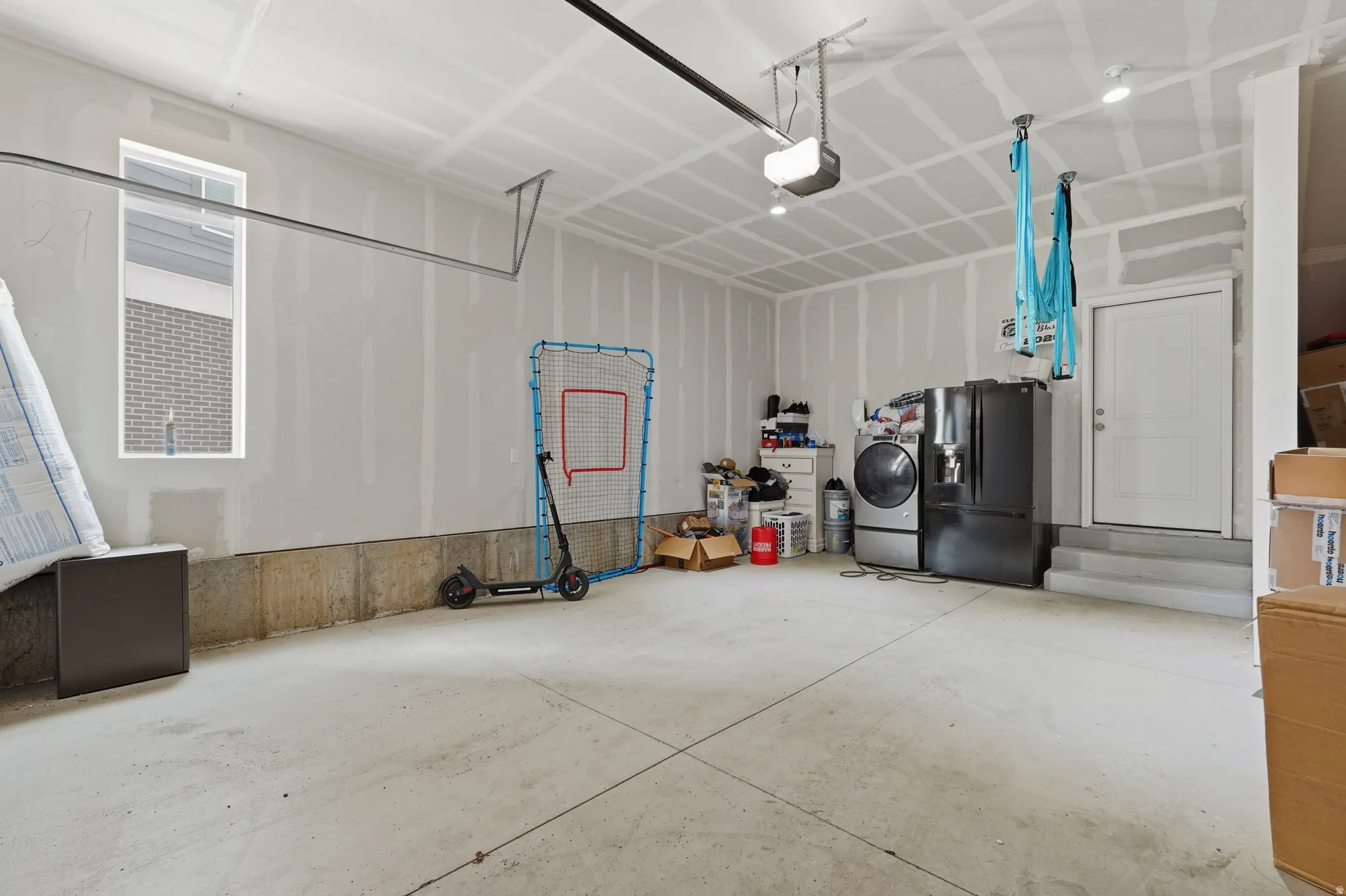 Spacious garage featuring a concrete floor, high ceilings, a window for natural light, an overhead garage door track system, and an interior access door
