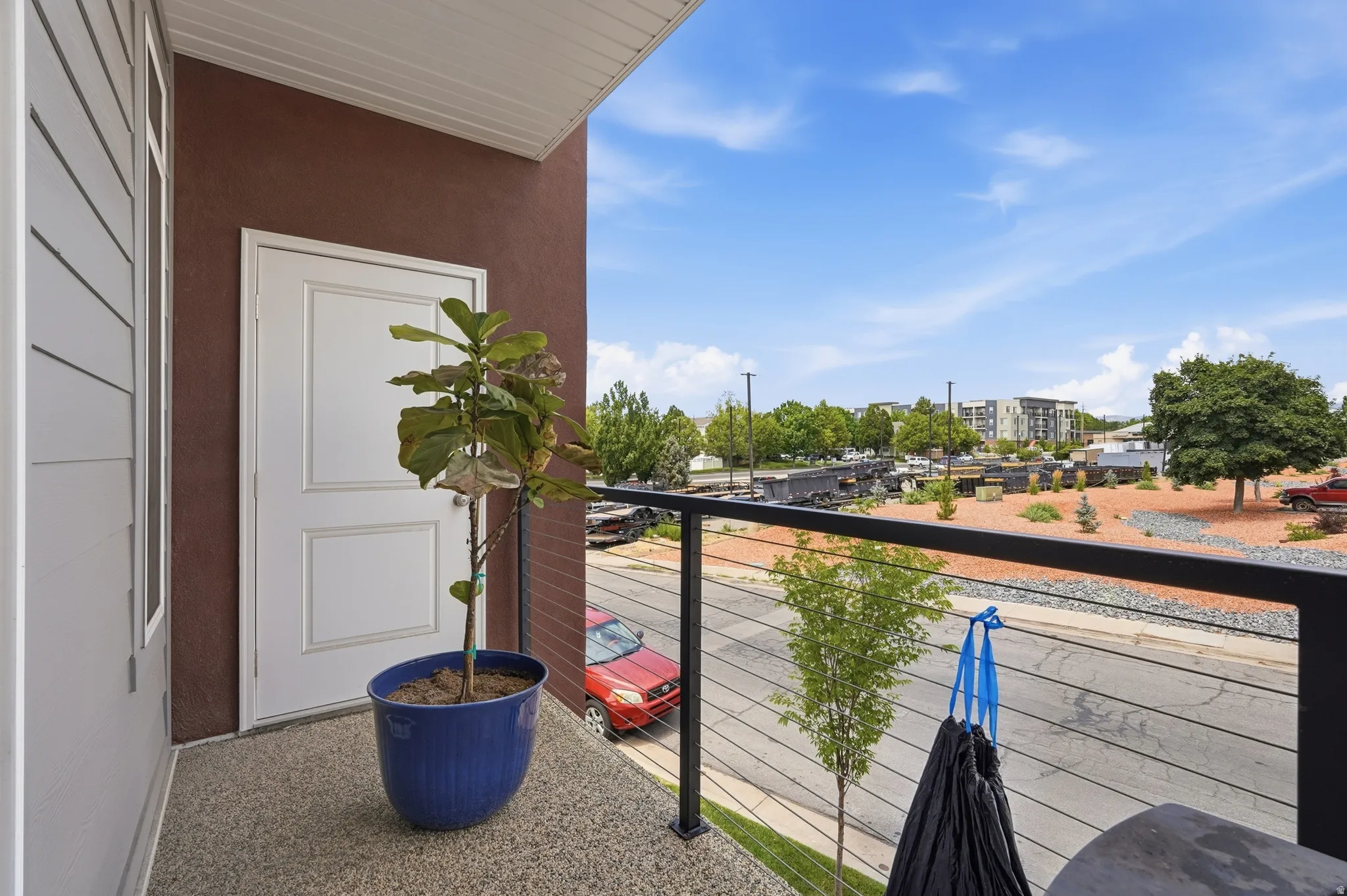 Private balcony featuring a textured floor, a white panel door, and a black cable railing system