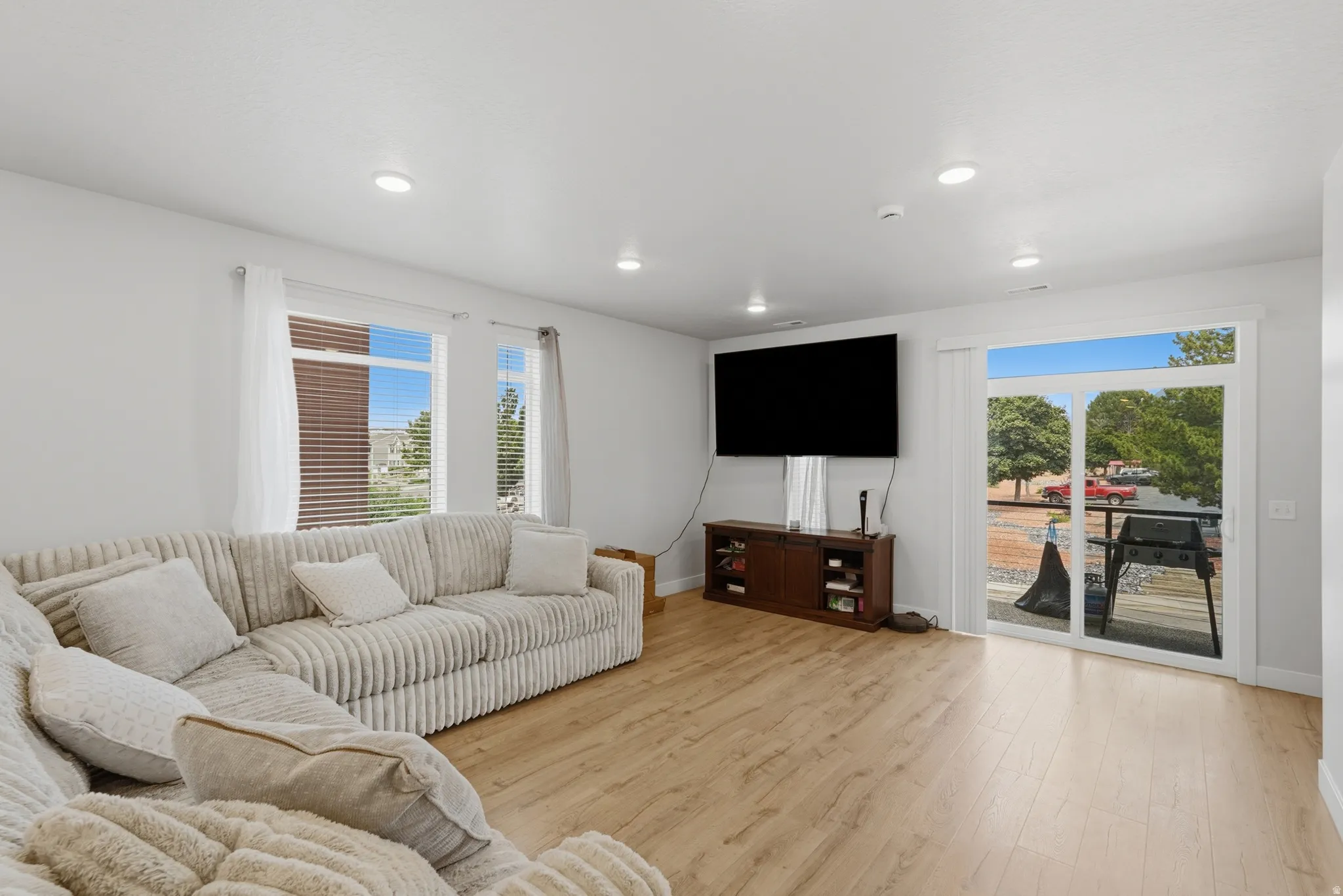 Spacious room featuring wood-finish flooring, recessed lighting, and white walls
