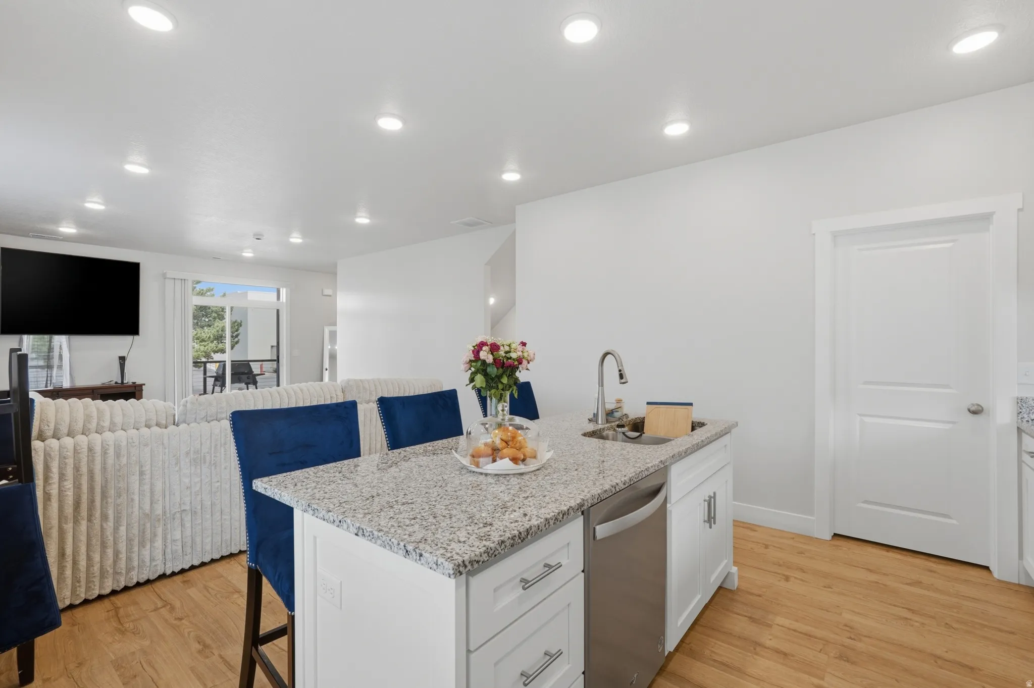 Kitchen island featuring white cabinetry, a stainless steel sink, and a speckled countertop