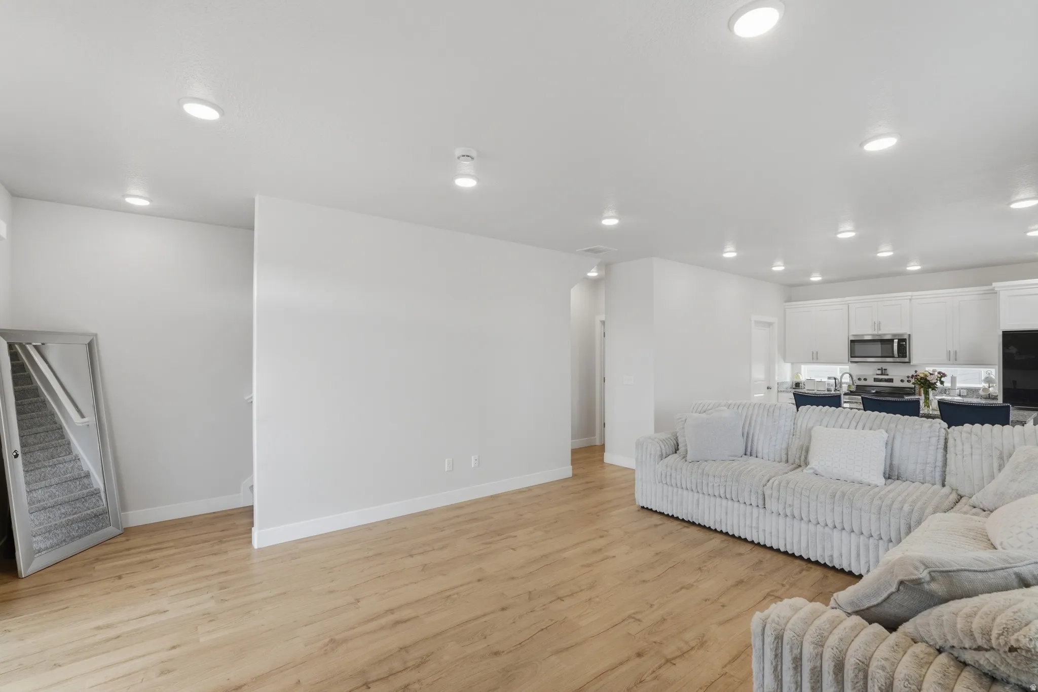 Open-concept living space featuring wood-finish flooring, recessed lighting, and white baseboards