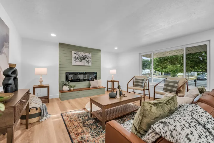 Spacious living area featuring wood-finish flooring, a contemporary linear fireplace set into a shiplap accent wall with a built-in bench, and recessed lighting