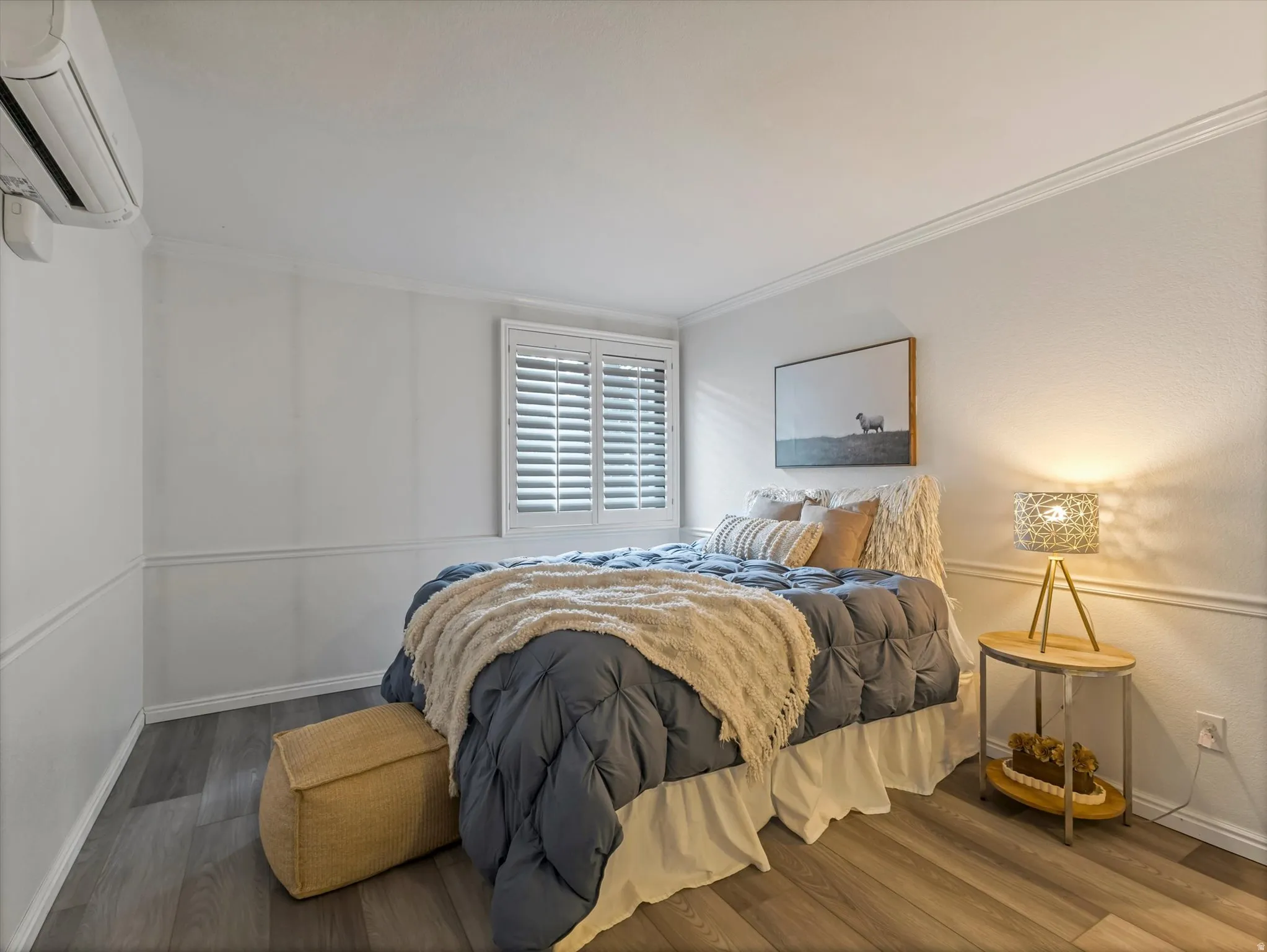 Interior room featuring wood-finish flooring, white wainscoting, and crown molding