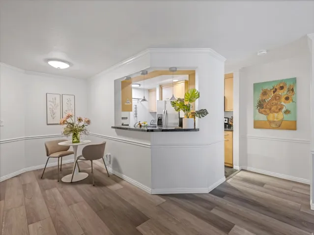 Dining area featuring wood-finish flooring, white wainscoting, and crown molding