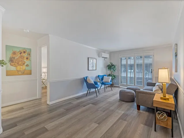 Living area featuring wood-finish flooring, two-tone wall treatment, and crown molding