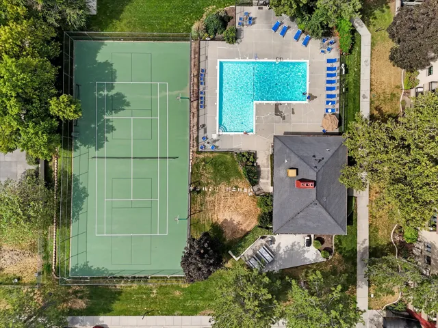 Full-sized tennis court with perimeter fencing alongside a spacious swimming pool area