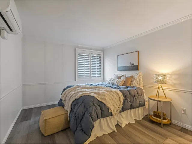 Interior room featuring wood-finish flooring, white wainscoting, and crown molding