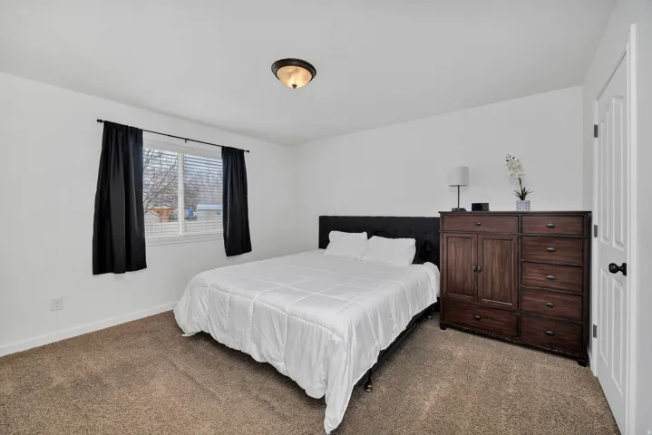 Bedroom featuring neutral tone carpeting and crisp white walls