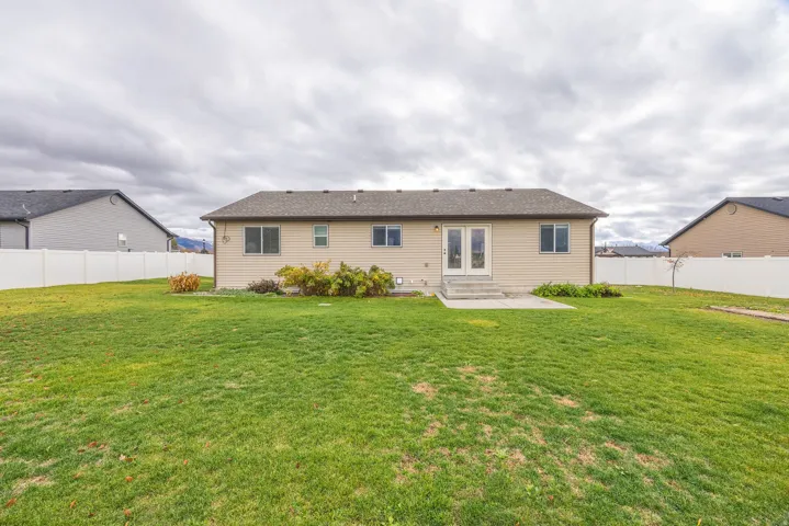Expansive backyard featuring a manicured lawn, full privacy fencing, and a concrete patio