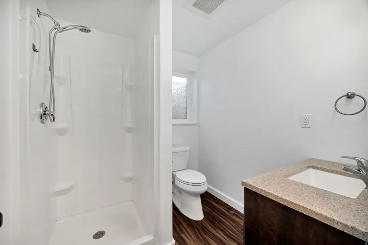 Full bathroom featuring a white walk-in shower with chrome fixtures and integrated shelving