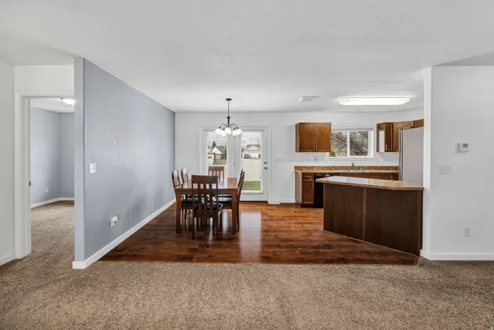 Dining area with wood-finish flooring, featuring a chandelier and patio door