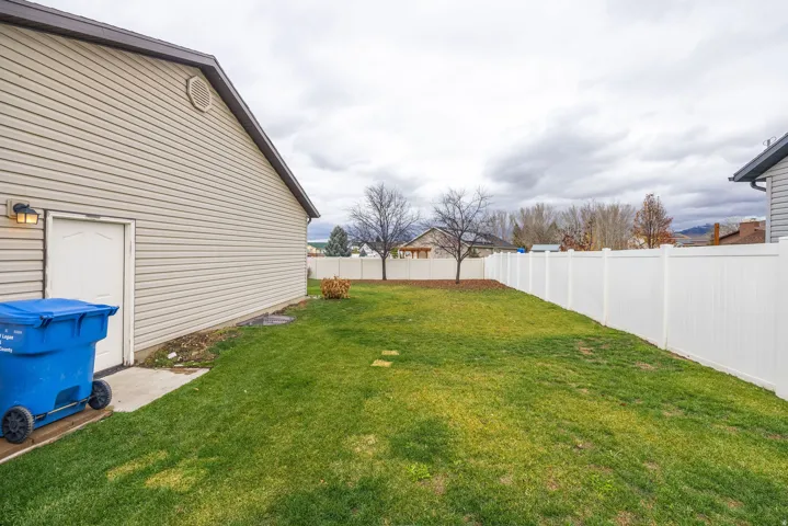Expansive grassy yard with a white privacy fence