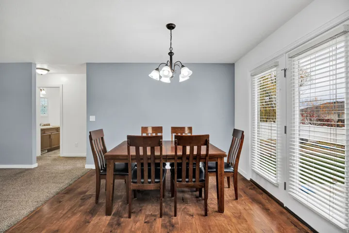 Dining area featuring wood-finish flooring, a contemporary chandelier, and light blue accent wall