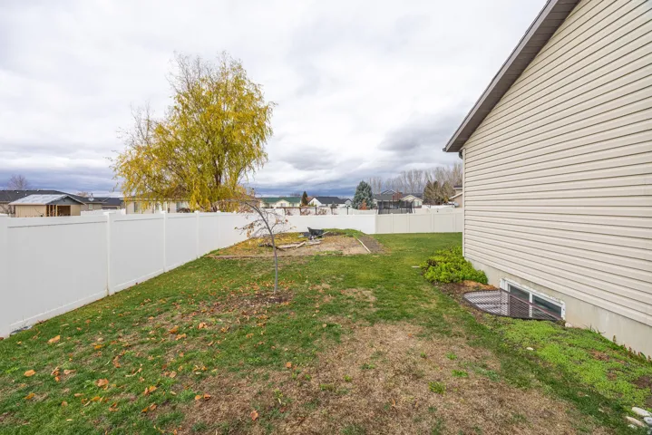 Expansive backyard featuring a white vinyl privacy fence, established green lawn, and mature trees