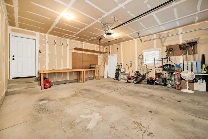 Spacious garage with concrete flooring and exposed drywall