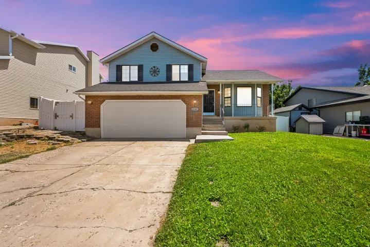 Two-story residence featuring a brick and siding exterior, an attached garage, a covered front porch, and a lawn