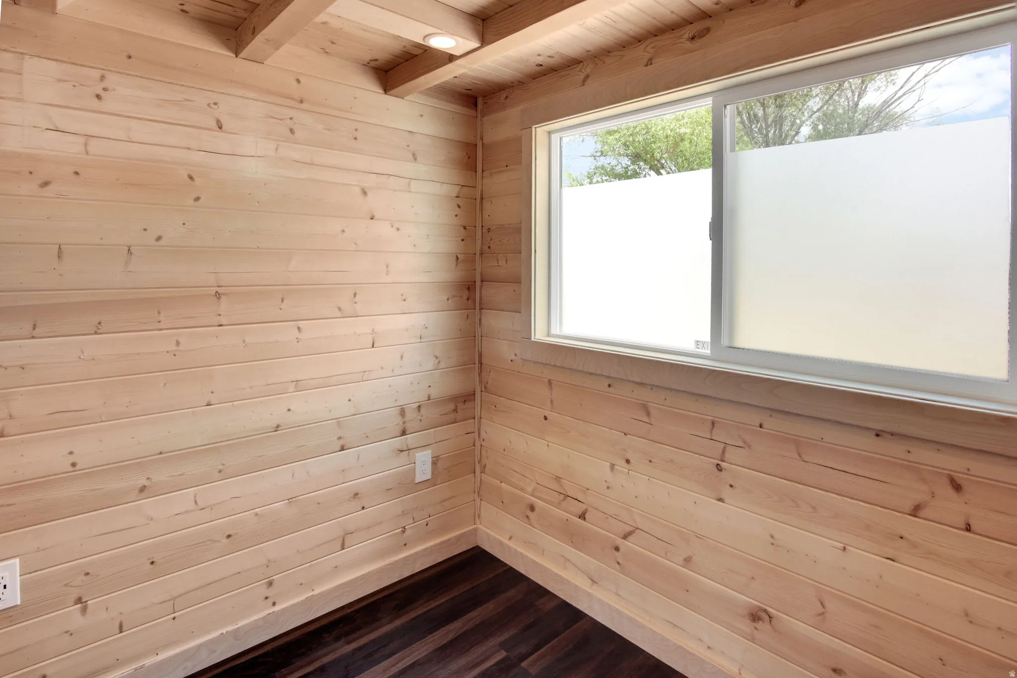Wood-paneled room featuring exposed ceiling beams and recessed lighting