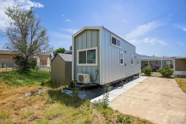 Modern tiny home with light blue board-and-batten siding and a shed roof