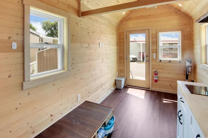 Interior space featuring light wood plank walls, a vaulted ceiling with exposed beam, and dark wood-finish flooring