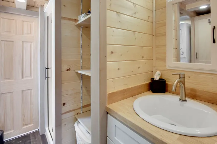 Bathroom vanity featuring a vessel sink with a brushed nickel faucet, wood-finish countertop, and white cabinetry