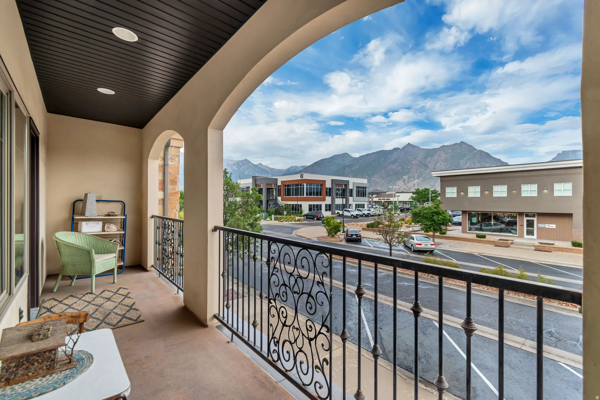 Balcony featuring a wrought iron railing, arched entry, recessed lighting, and a dark wood panel ceiling