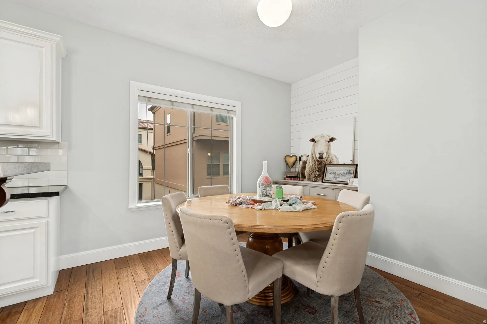 Open-concept dining area featuring wood-finish flooring, white baseboards, and a large window