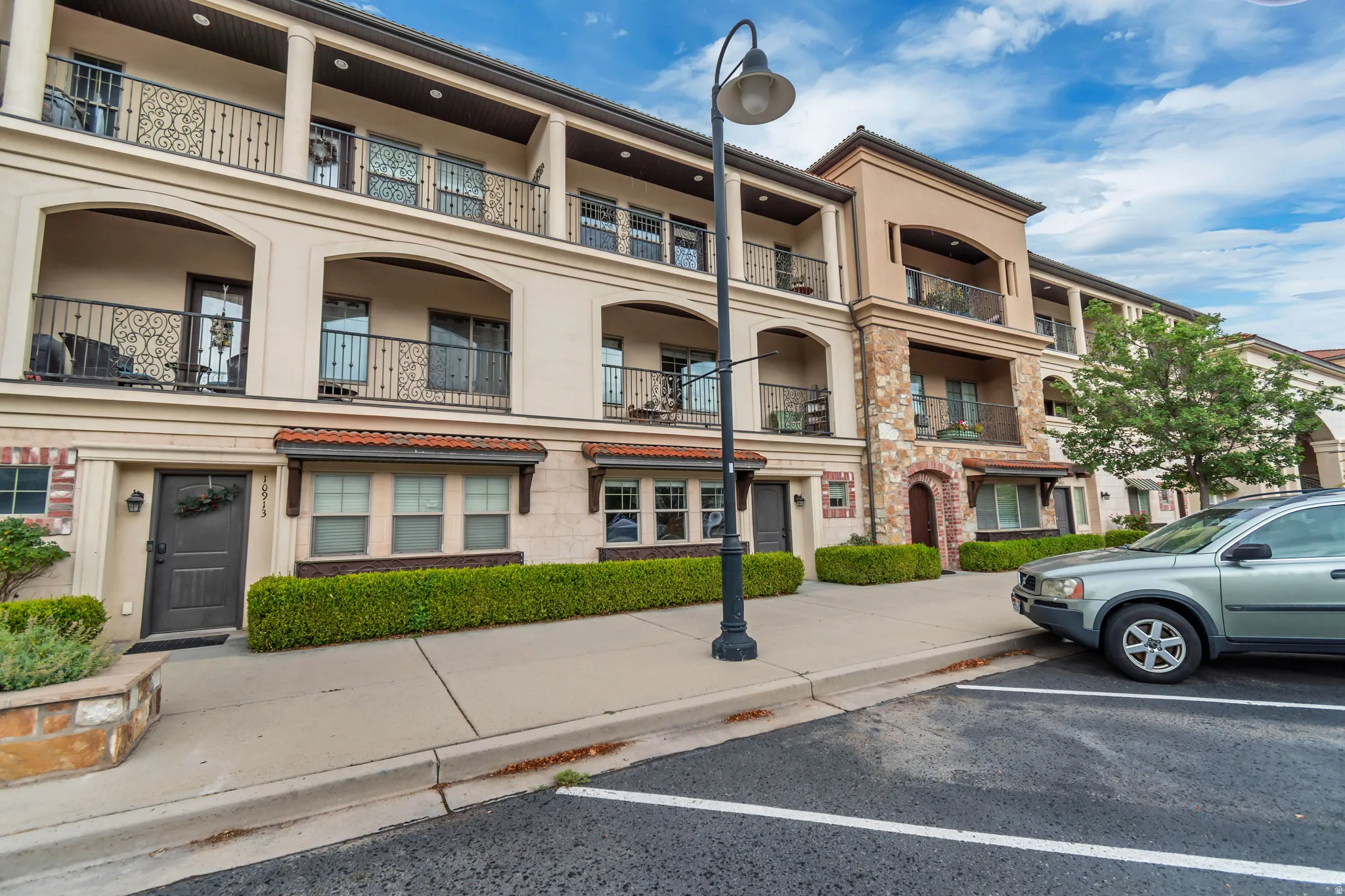 Multi-level facade featuring stucco siding, stone accents, and decorative wrought iron balconies