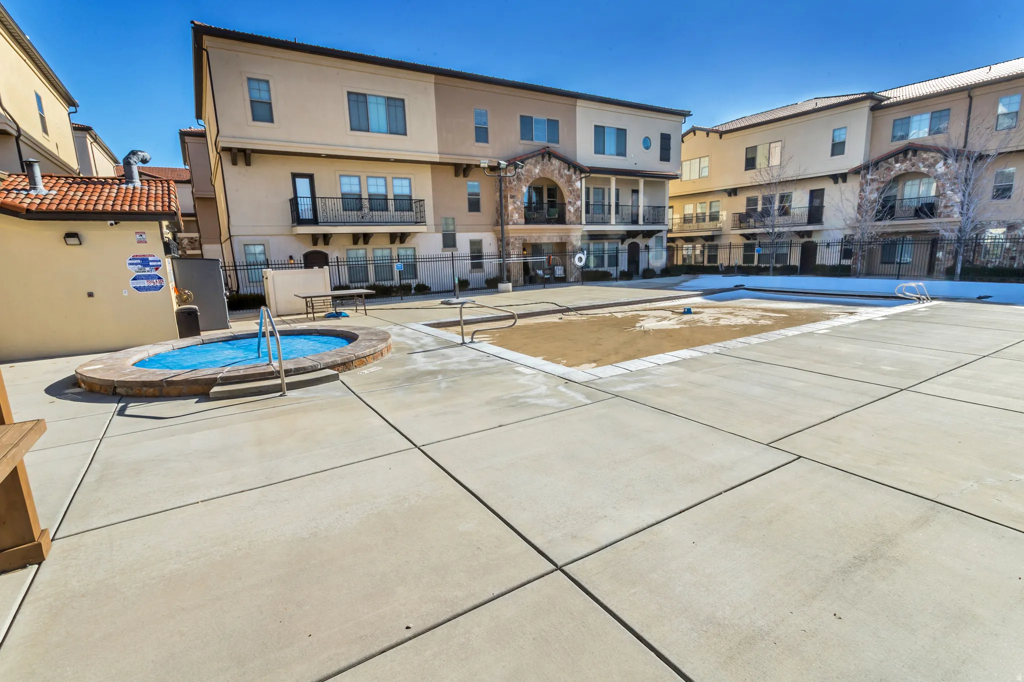 Community courtyard featuring a spa, a large rectangular pool area, and extensive concrete hardscaping