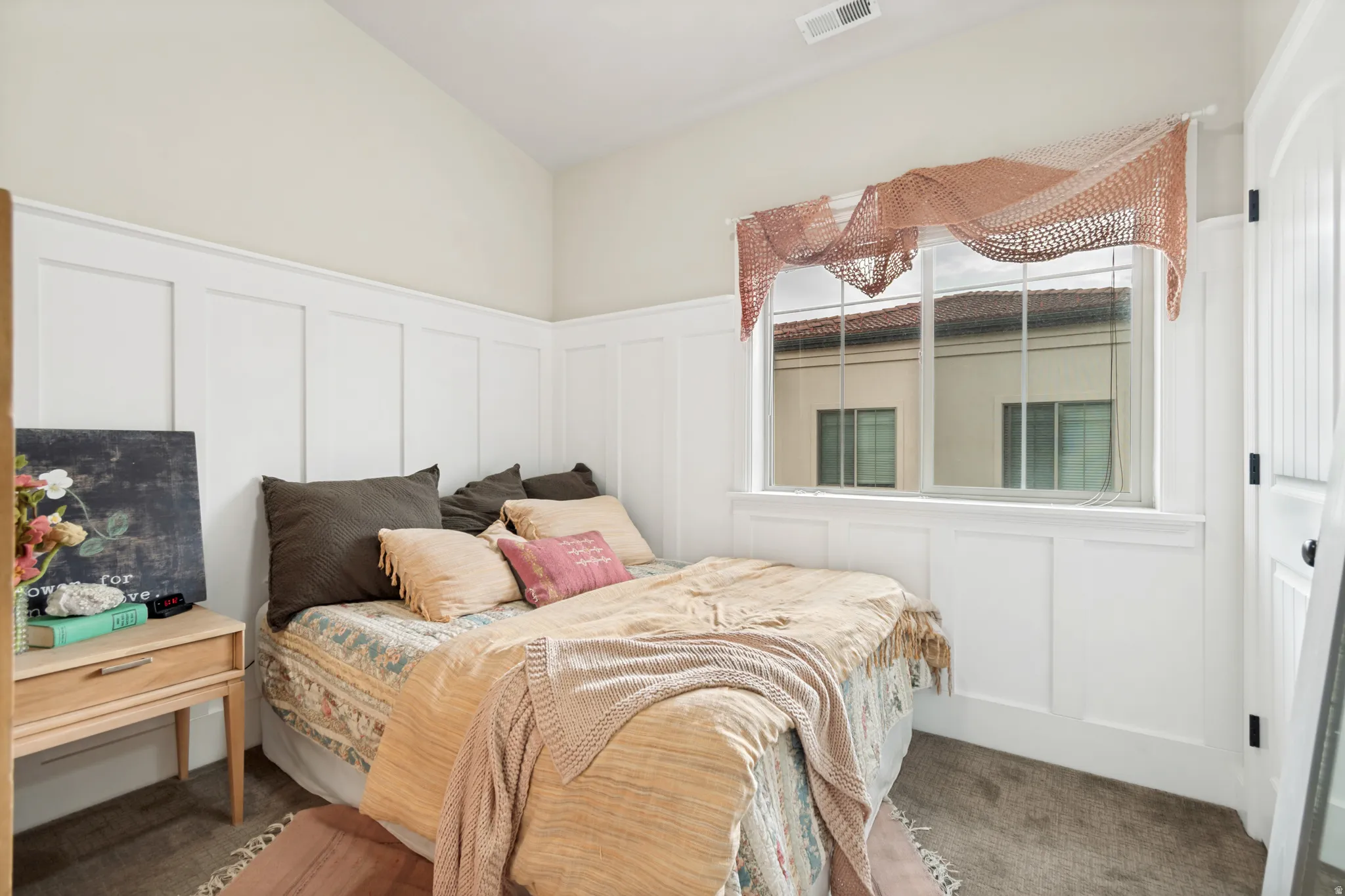 Room featuring wainscoting, an angled ceiling, and carpeted flooring