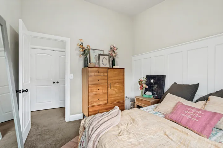 Bedroom featuring white board and batten wall paneling, light-toned wall paint, and gray carpet flooring