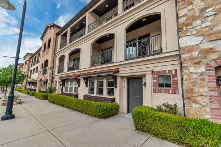 Multi-story stucco and stone facade featuring arched window and balcony openings