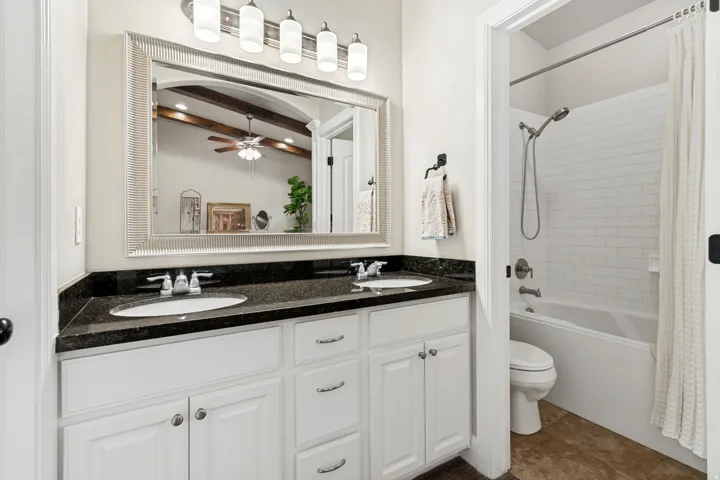 Bathroom vanity featuring dual undermount sinks, a dark countertop, and white cabinetry with brushed nickel hardware