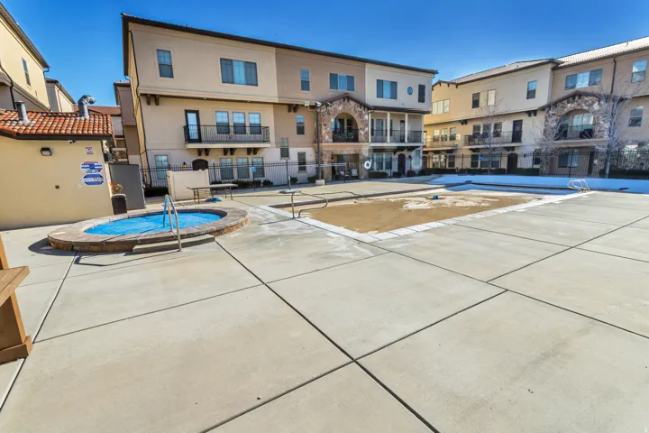 Community courtyard featuring a spa, a large rectangular pool area, and extensive concrete hardscaping
