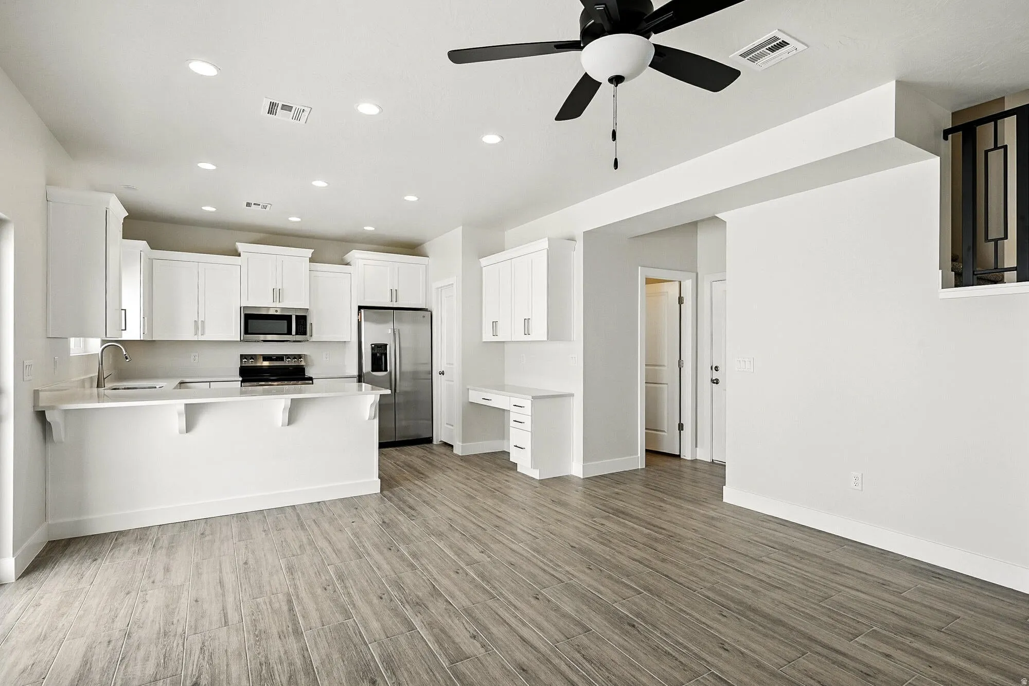 Open-concept kitchen featuring white cabinetry, stainless steel appliances, and a breakfast bar