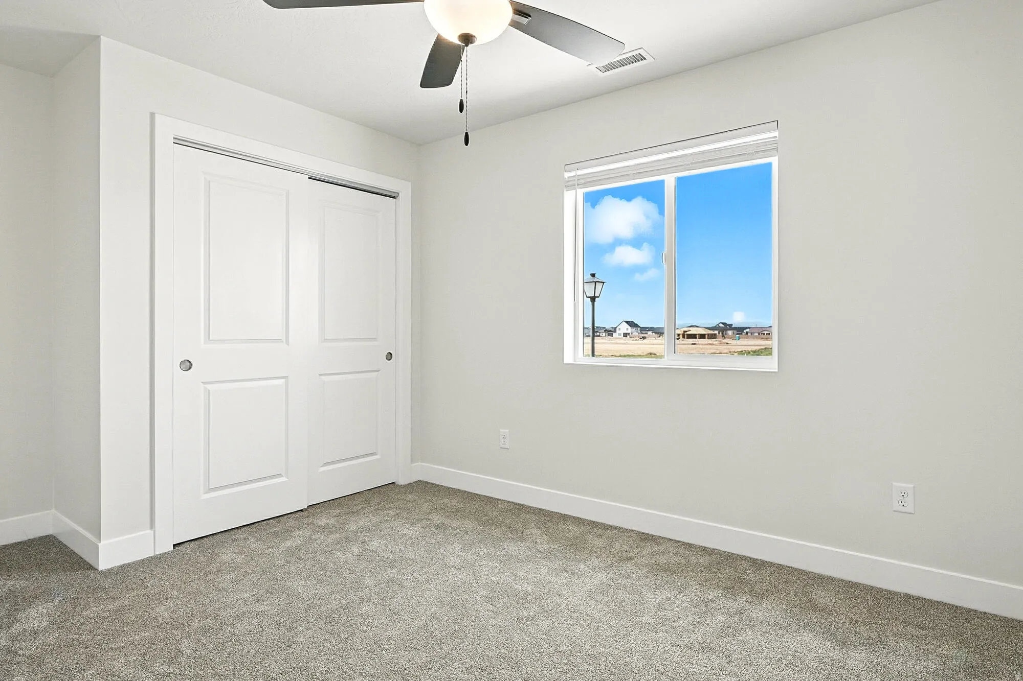 Interior room featuring light gray carpeting, white trim, and a ceiling fan with integrated lighting