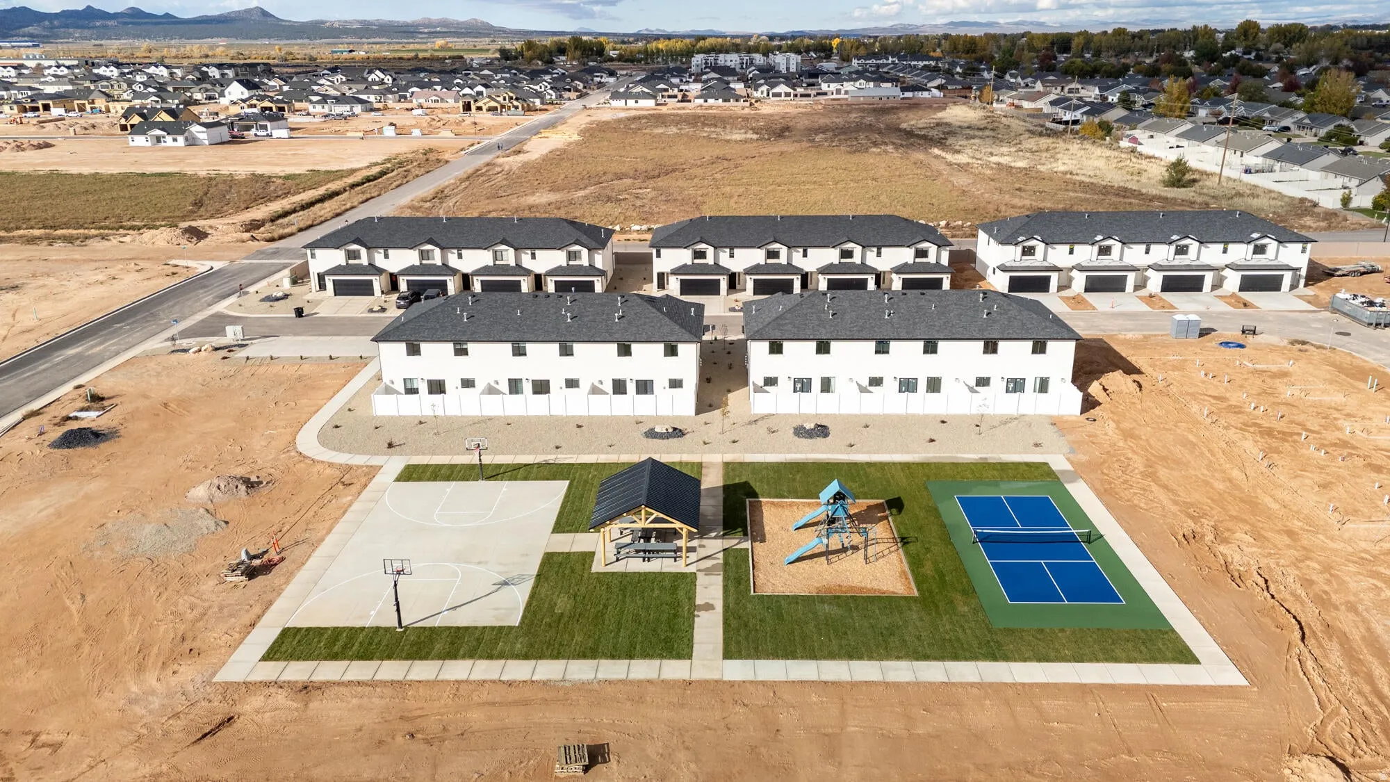 Aerial perspective showcasing multiple townhouse-style buildings with dark shingle roofing