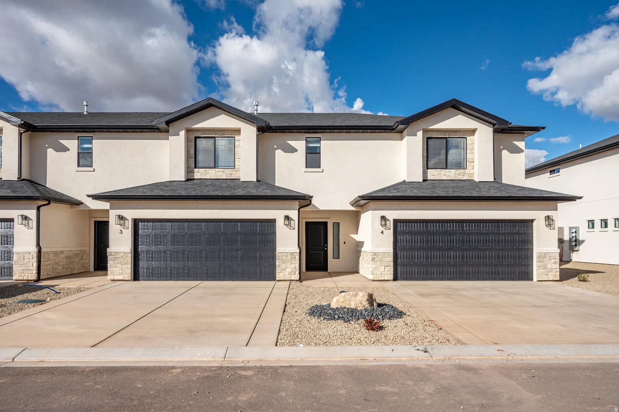 Modern stucco exterior with dark trim accents and stone veneer details
