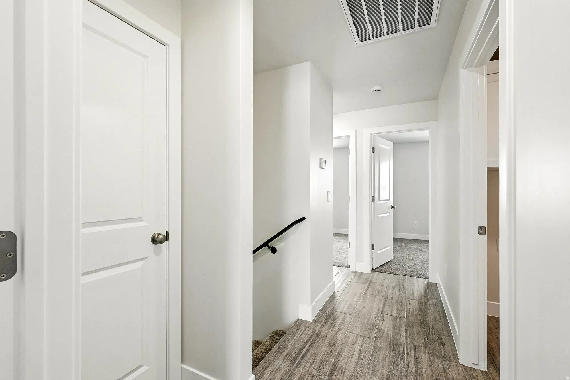 Bright hallway featuring wood-finish flooring, white walls, and white trim
