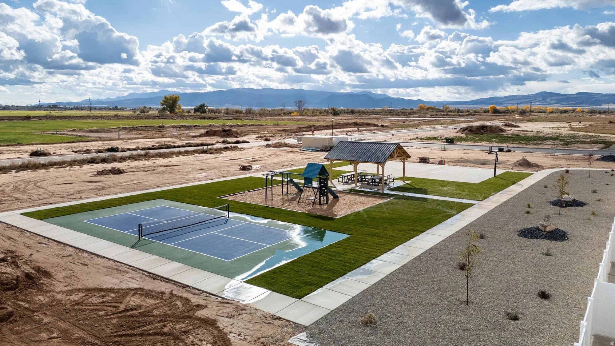 Community recreation area featuring a pickleball court, playground structure, and covered picnic pavilion