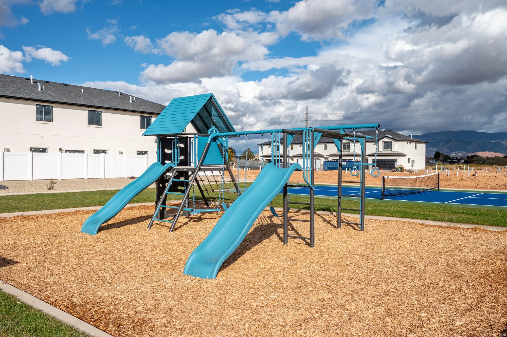 Community playground featuring a playset with slides and climbing elements, set on a wood chip surface