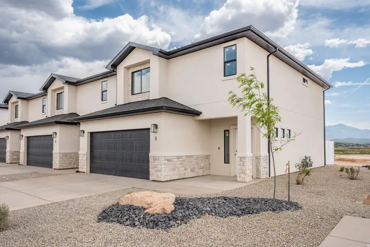 Modern townhome exterior featuring light-colored stucco and stone veneer accents
