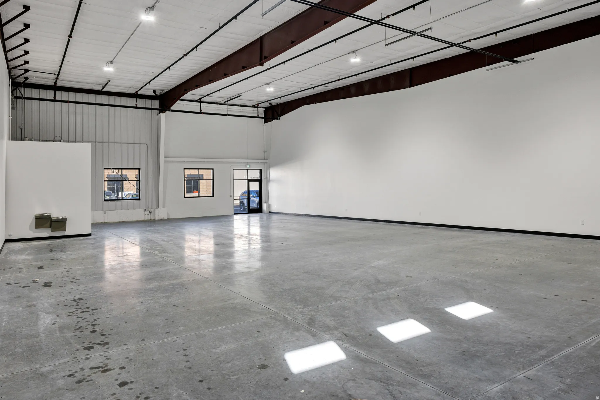 Spacious commercial interior featuring a polished concrete floor and high ceilings with exposed structural beams
