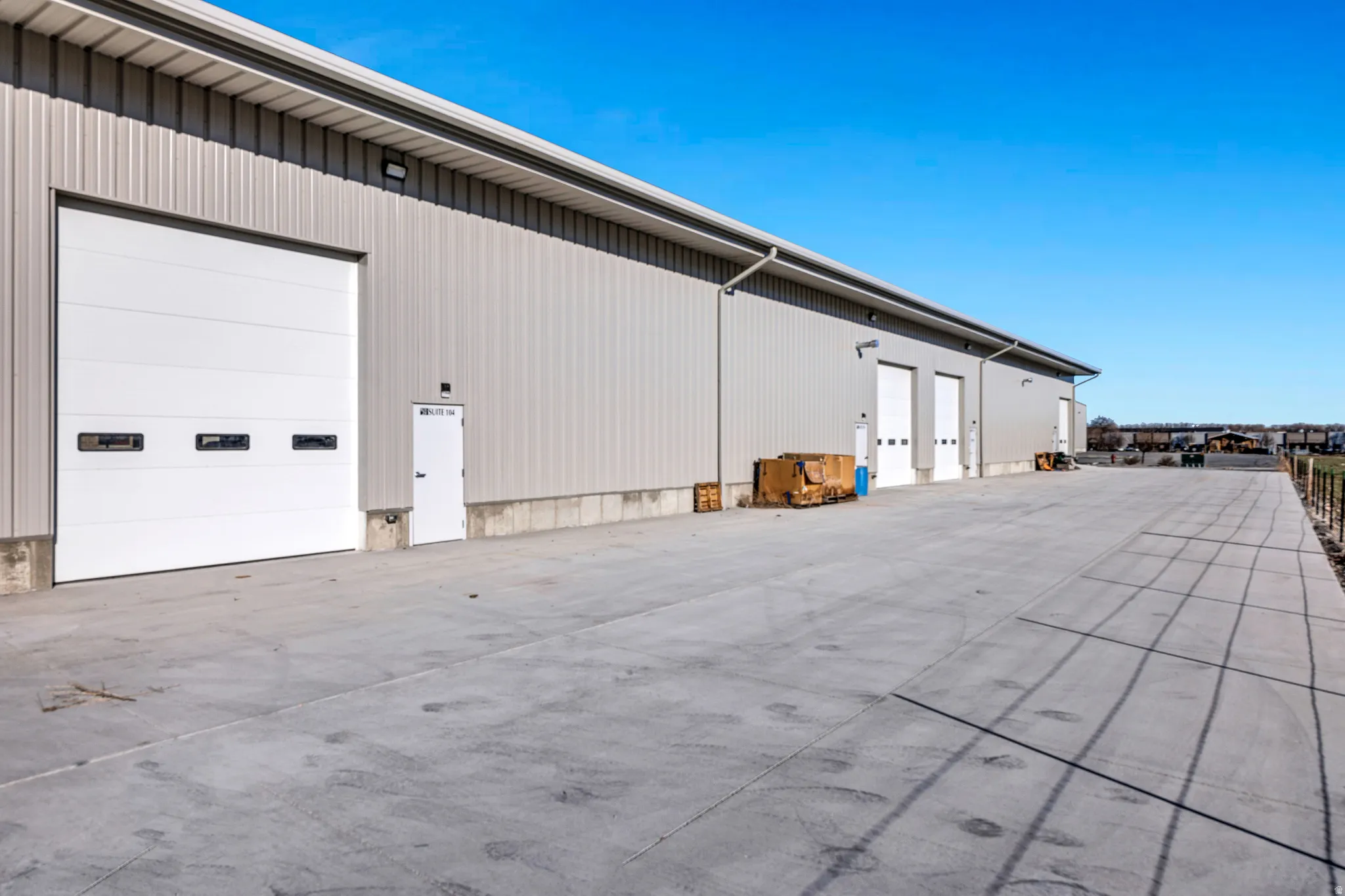 Commercial building featuring multiple overhead doors, a metal siding exterior, concrete foundation, and a concrete apron