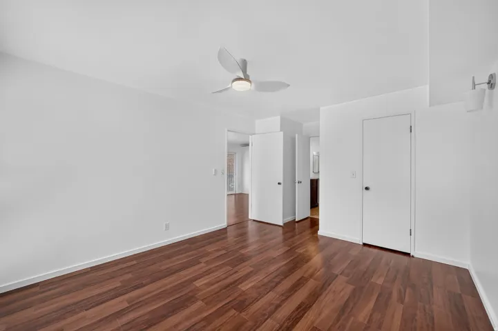 Spacious room featuring wood-finish flooring, white walls, and a contemporary ceiling fan with integrated lighting