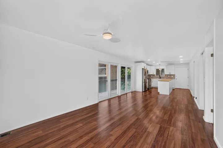 Open-concept living area featuring wood-finish flooring and white walls