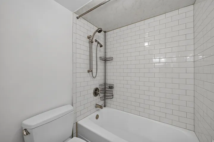 White subway tile shower surround with a built-in bathtub, a multi-function showerhead, and brushed nickel fixtures