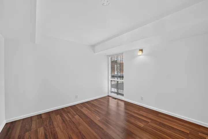 Room featuring wood-finish flooring, white walls, and a recessed ceiling